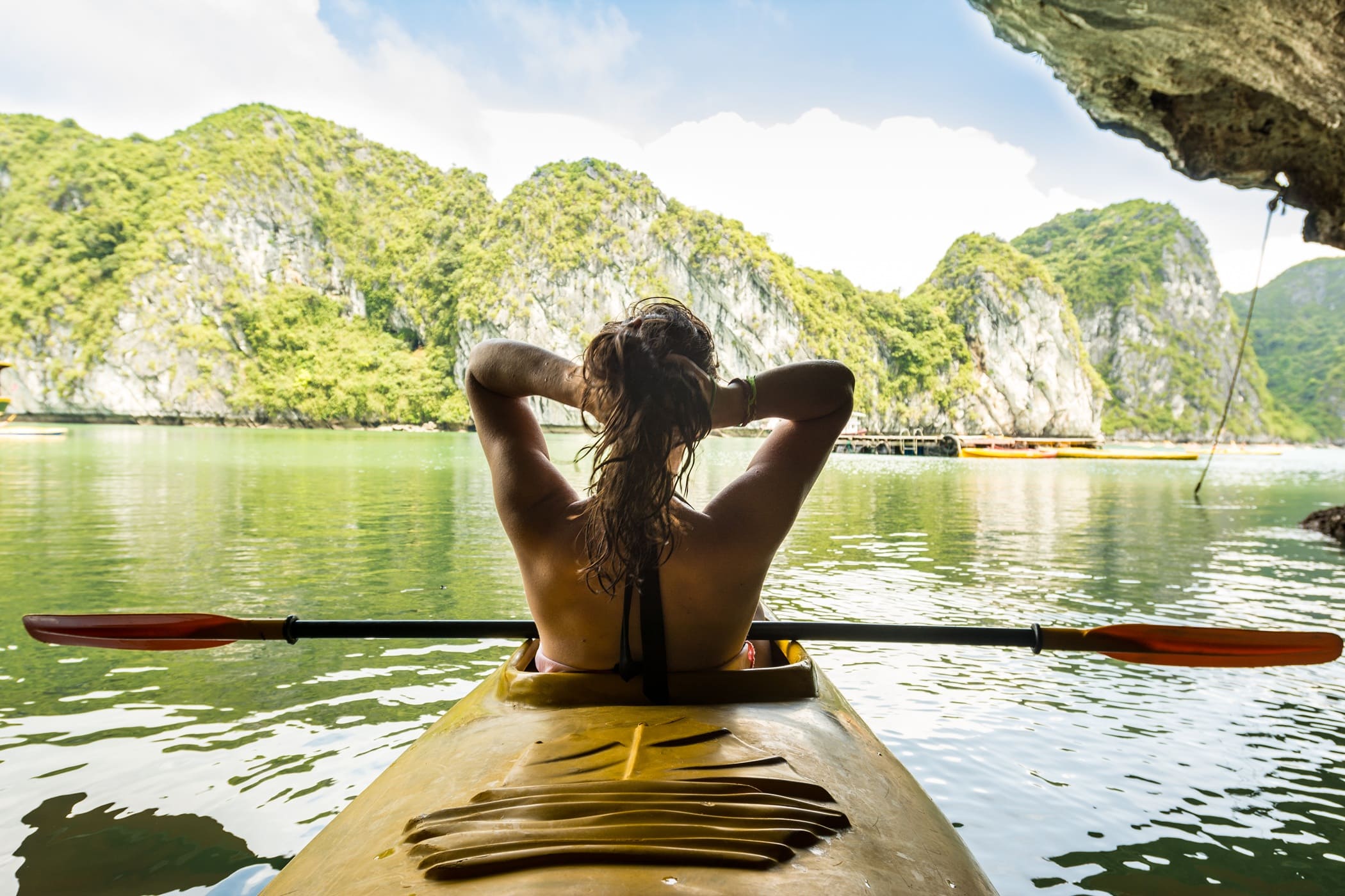 A woman tiesback her hair while staring at the karst formations reaching our of the sea