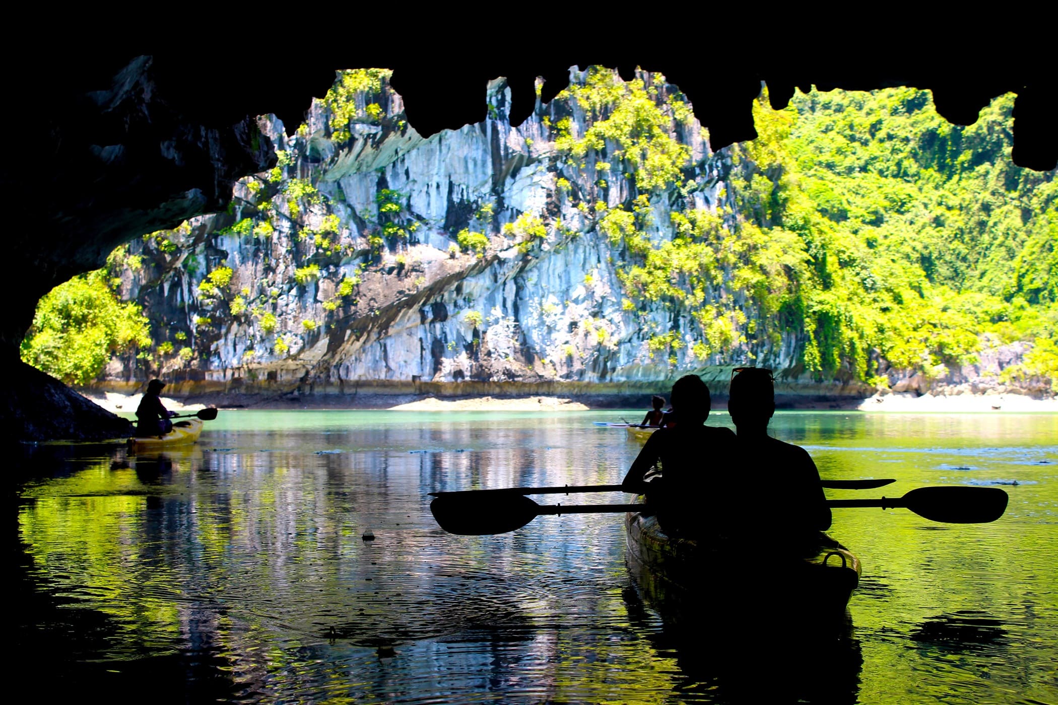 The silhouettes of people kayaking inside of a cave in Lan Ha Bay, Cat Ba National Park, close to Halong Bay, Vietnam